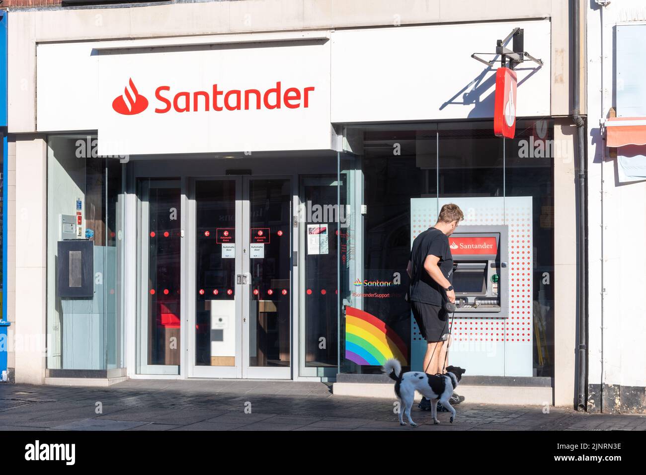 Banco Santander, una sucursal de la calle principal del banco con un hombre usando el cajero automático, Reino Unido Foto de stock