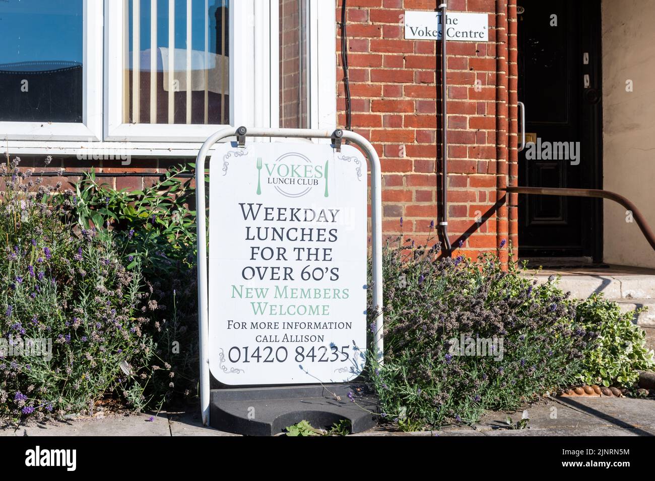 Firme anunciando un Club de Almuerzo, Comidas de día de semana para los mayores de 60, fuera del Centro de Vokes en Alton, Hampshire, Inglaterra, Reino Unido Foto de stock