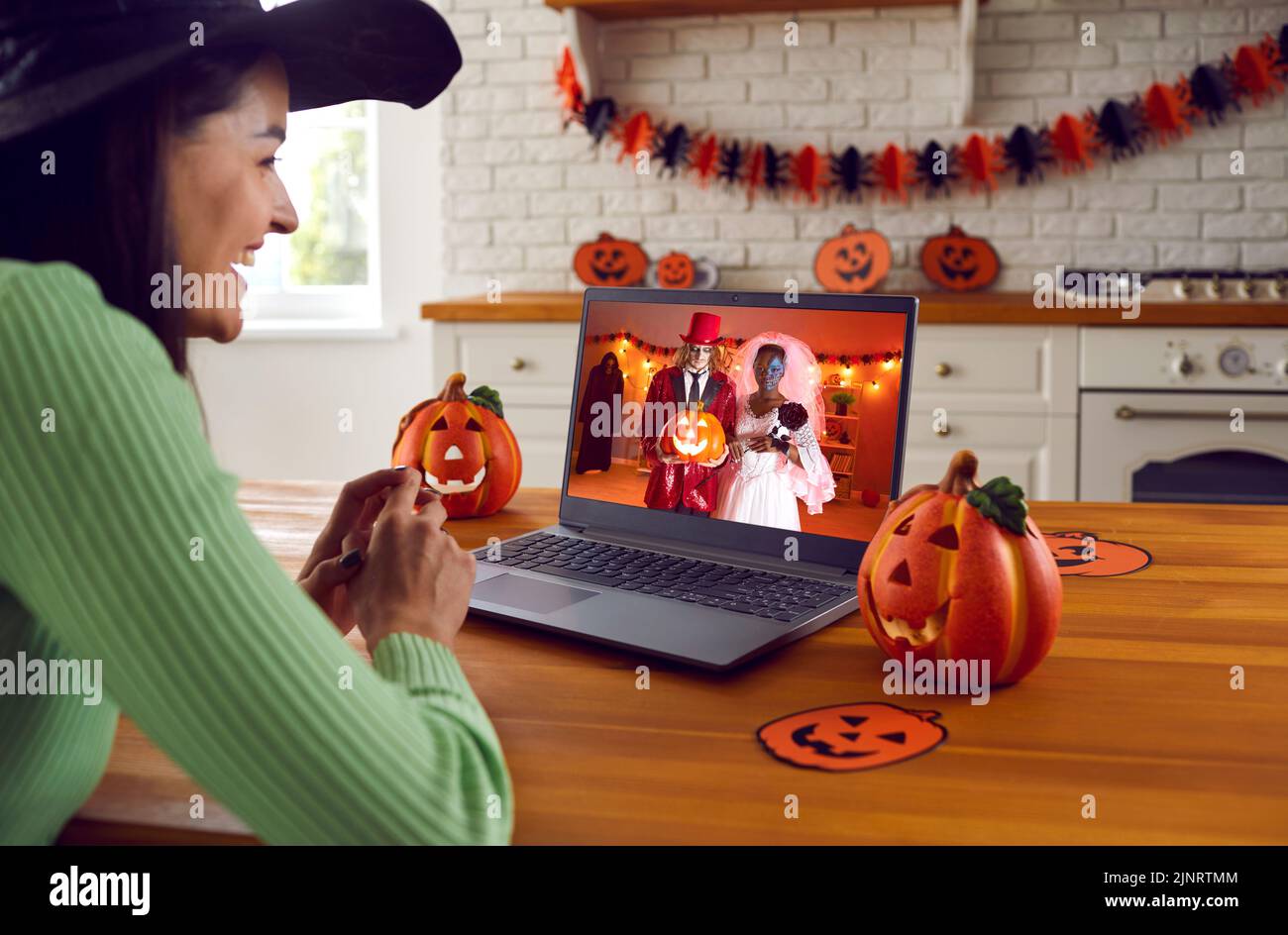 Mujer feliz usando el ordenador portátil y teniendo en línea fiesta de disfraces de Halloween con sus amigos Foto de stock