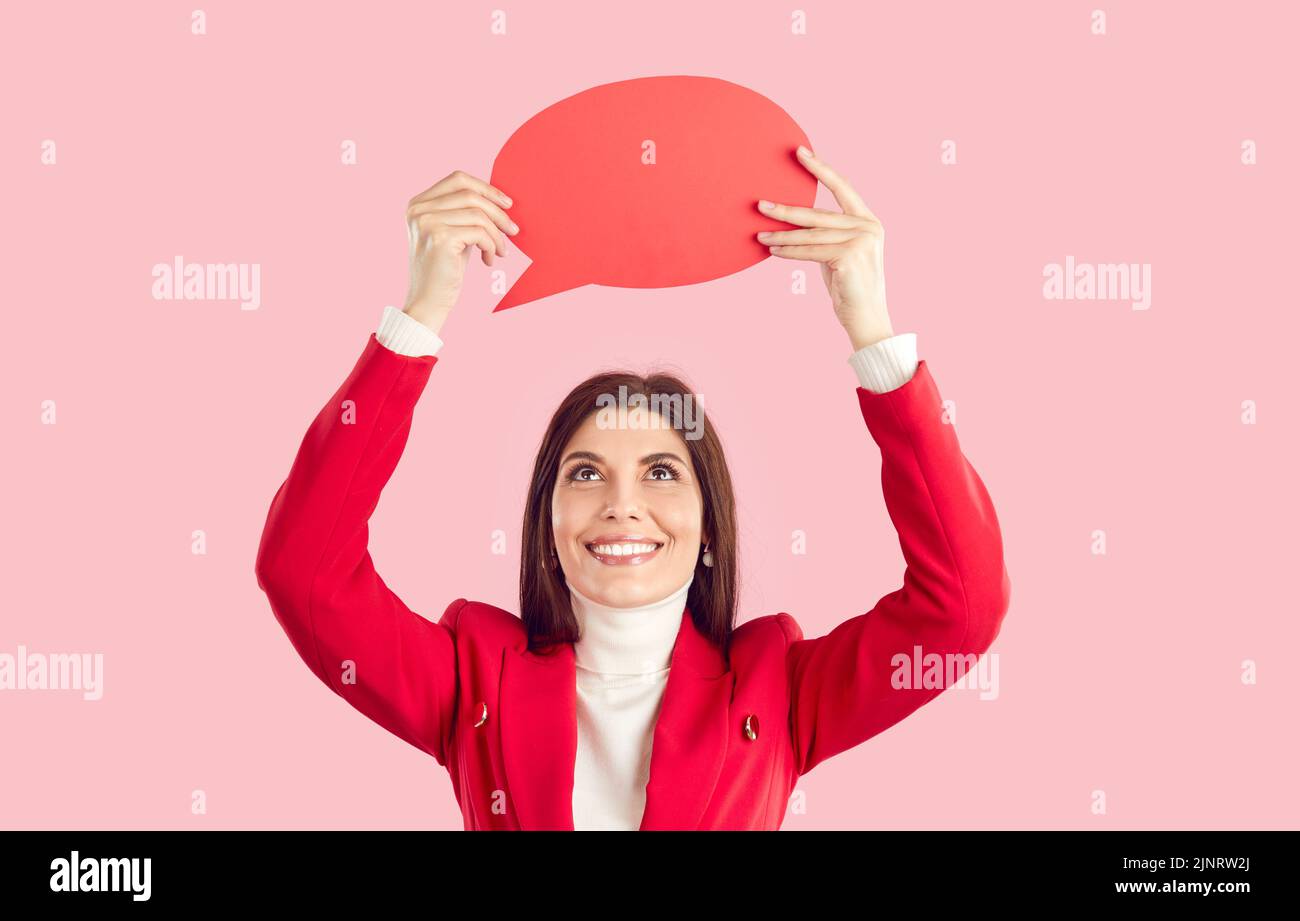 Mujer joven feliz sobre fondo rosa mostrando rojo mockup habla globo y sonriendo Foto de stock