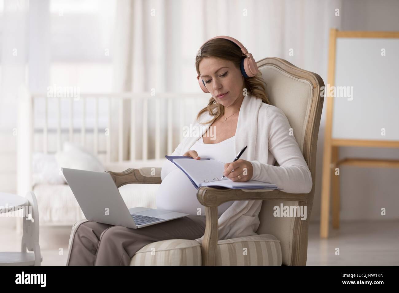 Mujer embarazada utiliza portátil Obtener consulta en línea, escribe información útil Foto de stock