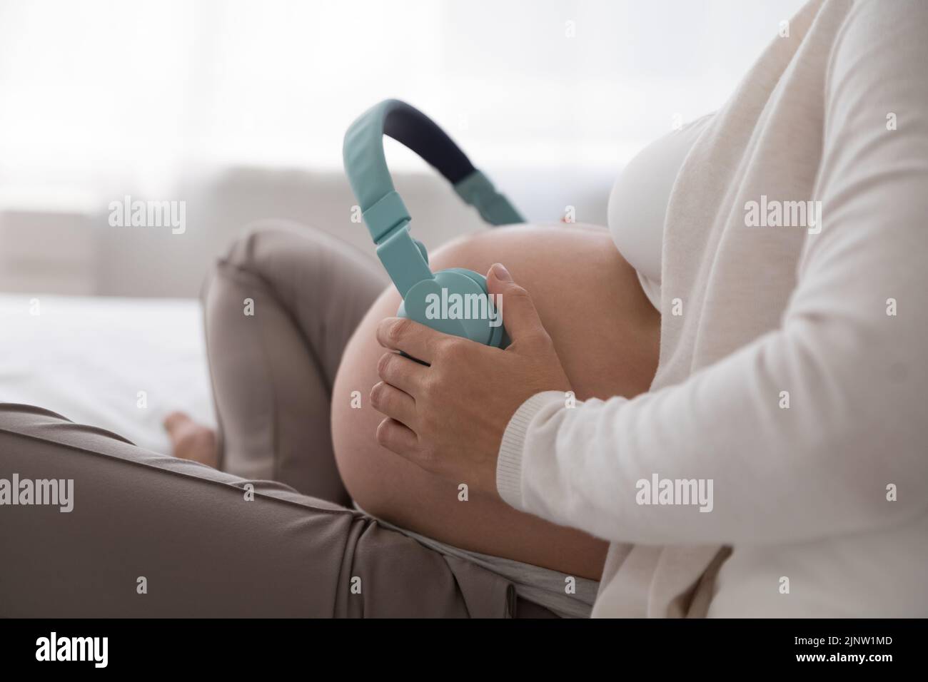 Mujer embarazada poner auriculares en el vientre escuchar música para el feto Foto de stock