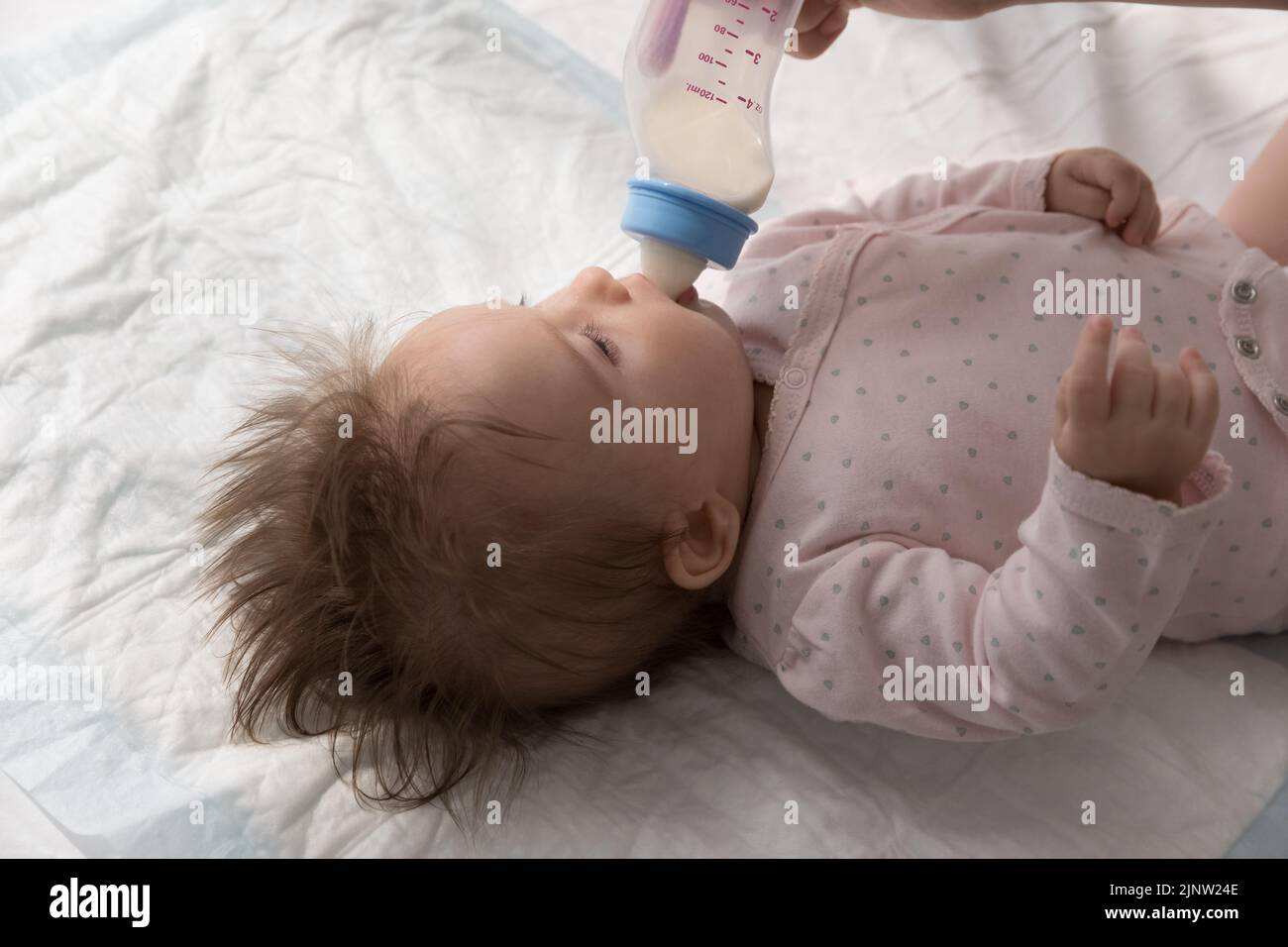 El adorable bebé recién nacido bebe leche materna de las madres del biberón Foto de stock