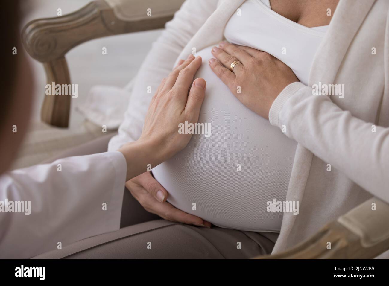 Closeup que cuida doula consulta a la mujer embarazada toque su vientre, closeup Foto de stock