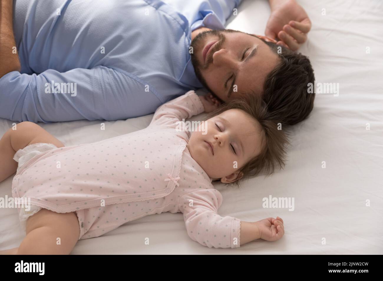 Padre cansado se queda dormido cerca del recién nacido, cerca Foto de stock