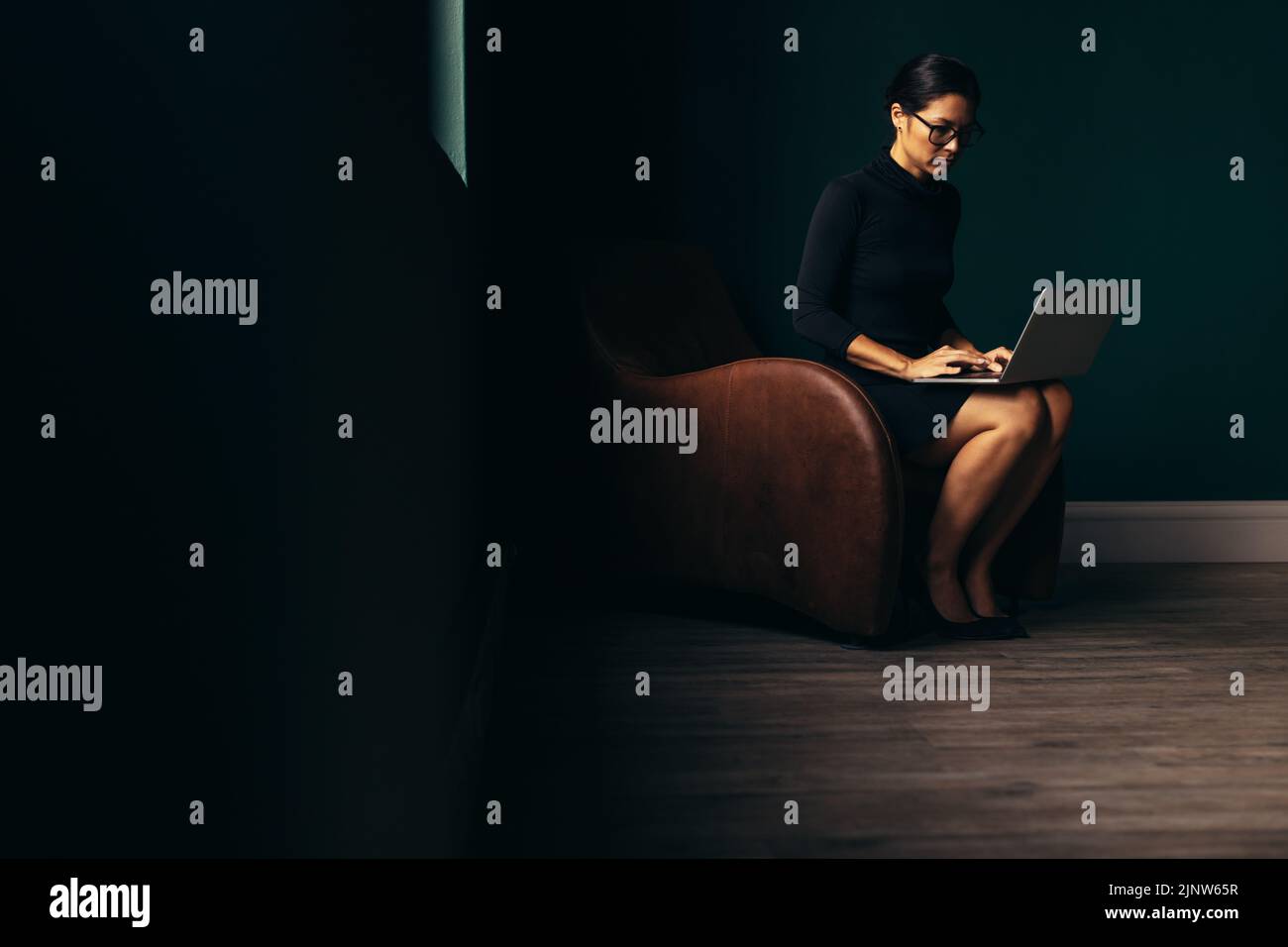 Mujer ocupada comprobando correos electrónicos en su portátil. Mujer de negocios asiática que trabaja con un ordenador portátil en la oficina. Foto de stock