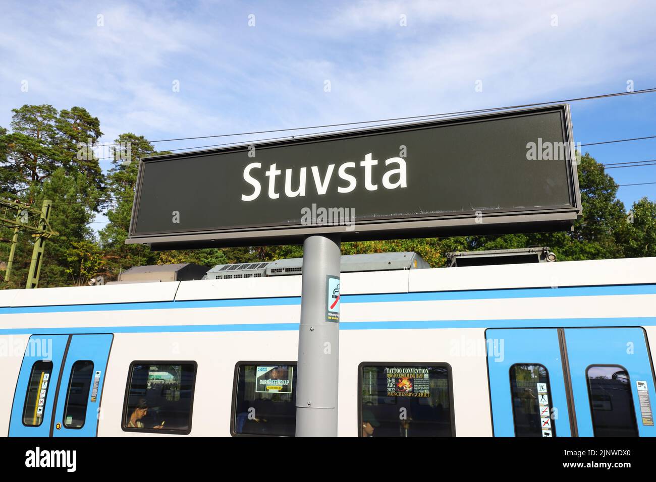 Stuvsta, Suecia - 11 de agosto de 2022: Vista de cerca de la estación de ferrocarril de Stuvsta, cartel con el nombre de la plataforma con un tren de transporte público de Estocolmo Foto de stock