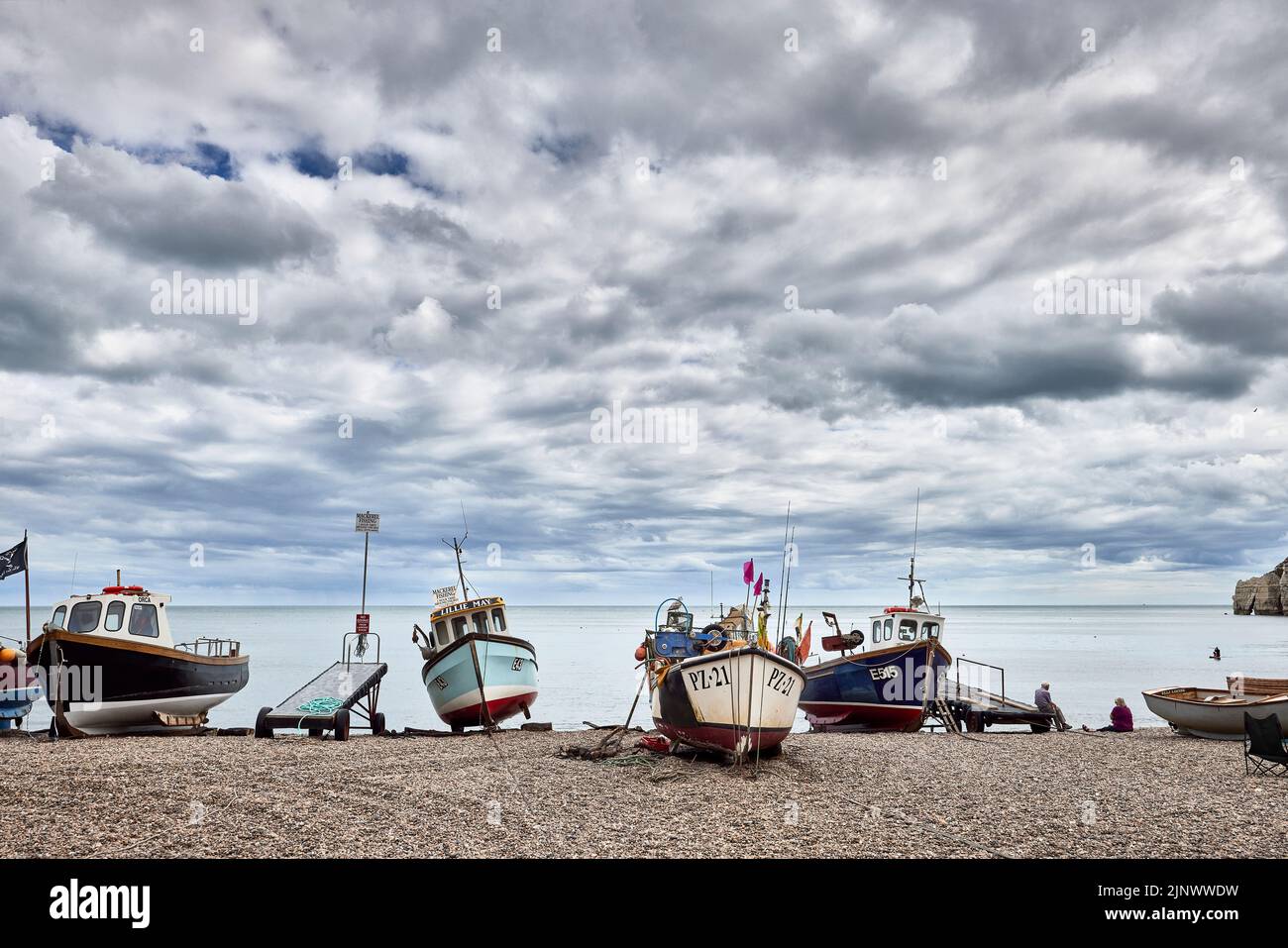Pequeños barcos de pesca tradicionales se embarcaron en la playa de guijarros pedregosos de Beer, un pequeño pueblo costero de Devon en la costa jurásica Foto de stock