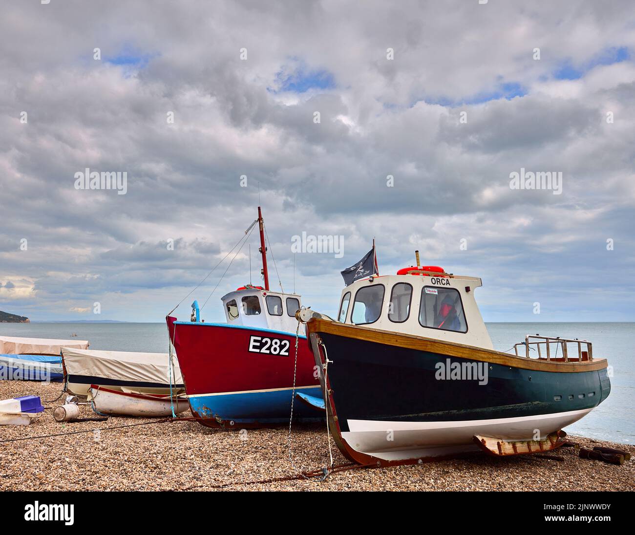 Pequeños barcos de pesca tradicionales se embarcaron en la playa de guijarros pedregosos de Beer, un pequeño pueblo costero de Devon en la costa jurásica Foto de stock
