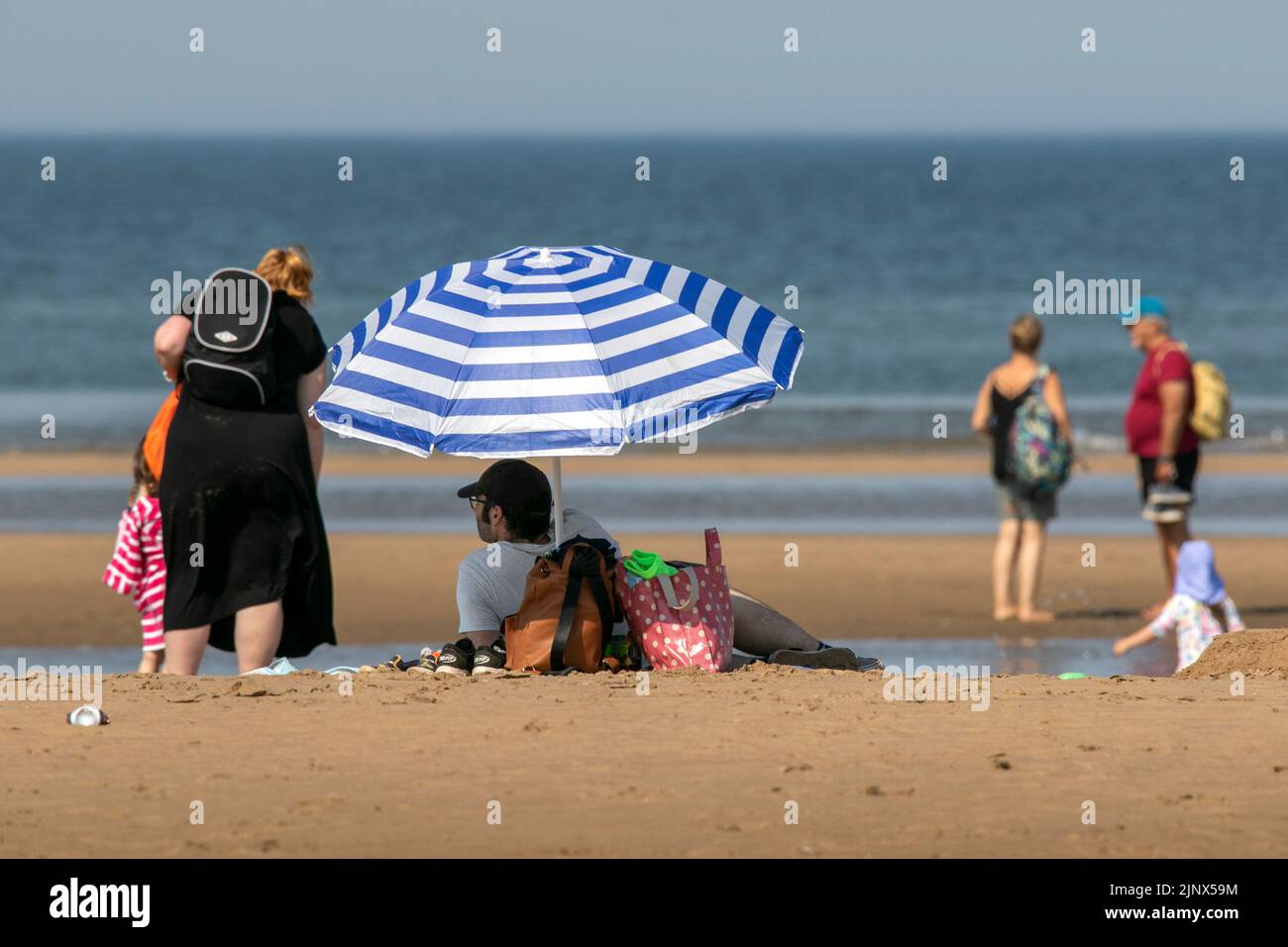 Southport, Merseyside, 14 de agosto de 2022. La gente se dirige hacia las doradas arenas de la playa Southport Beach para refrescarse y divertirse en las sofocantes olas que cubren el Reino Unido. Crédito: Cernan Elias/Alamy Live News Foto de stock