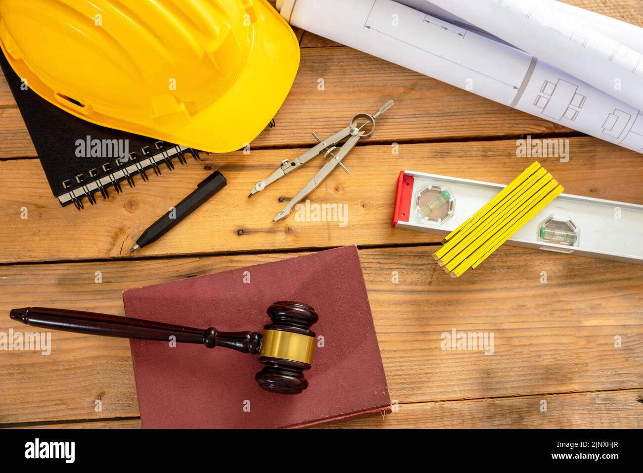 Construcción y derecho laboral en plano. Juzgue el martillo y las herramientas de ingeniería sobre una mesa de madera, vista superior. Foto de stock