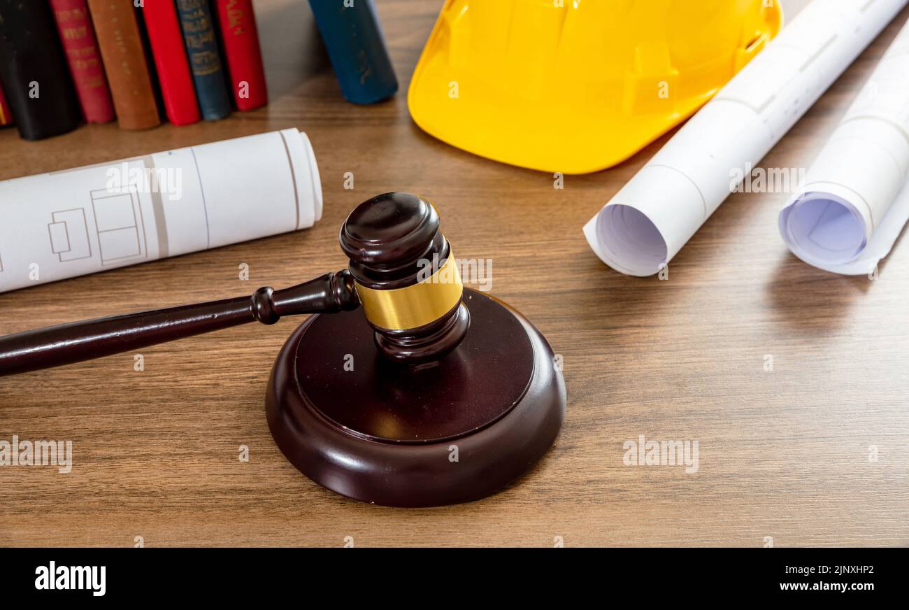 Construcción y Derecho laboral. Juzgue los dibujos del mazo y de la construcción en una mesa de madera, vista de cerca. Foto de stock