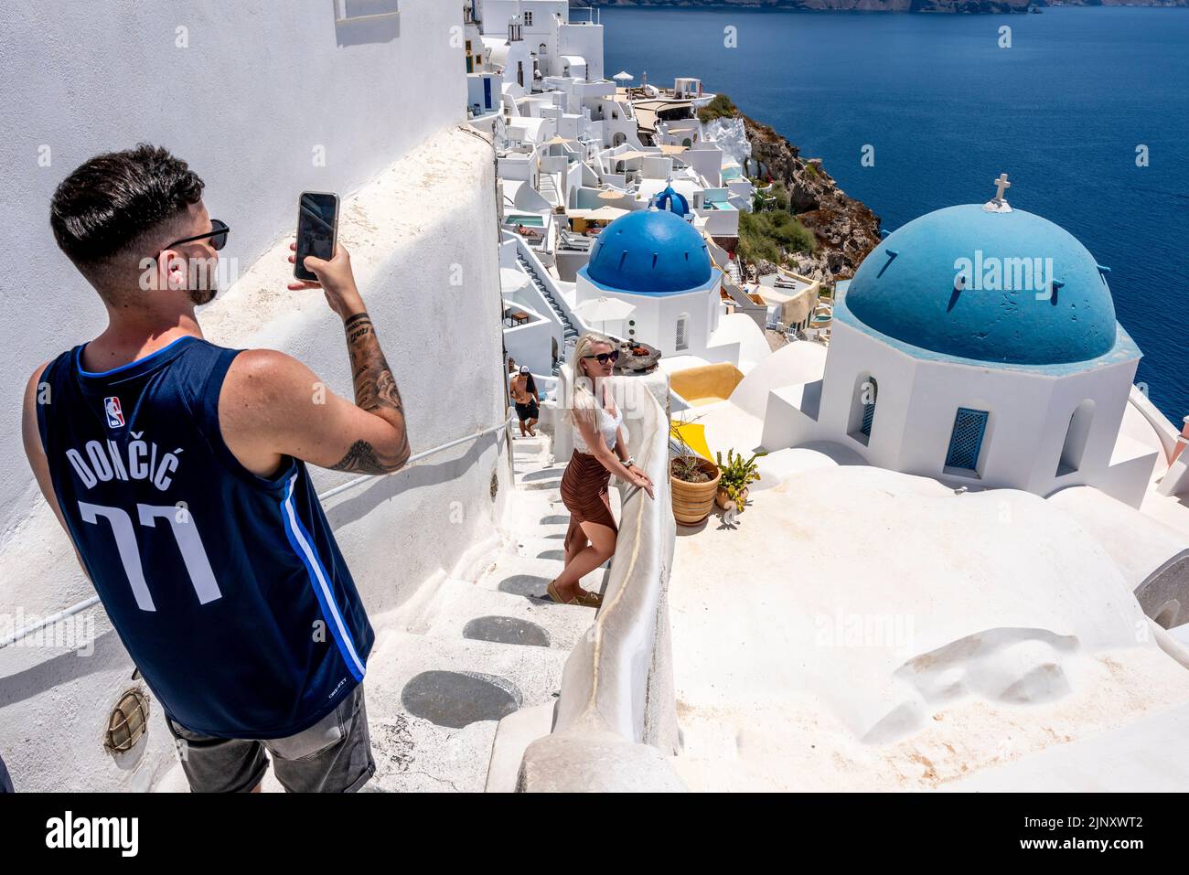 Una mujer joven posa para las fotos en Un mirador clásico en la ciudad de Oia, Santorini, islas griegas, Grecia. Foto de stock