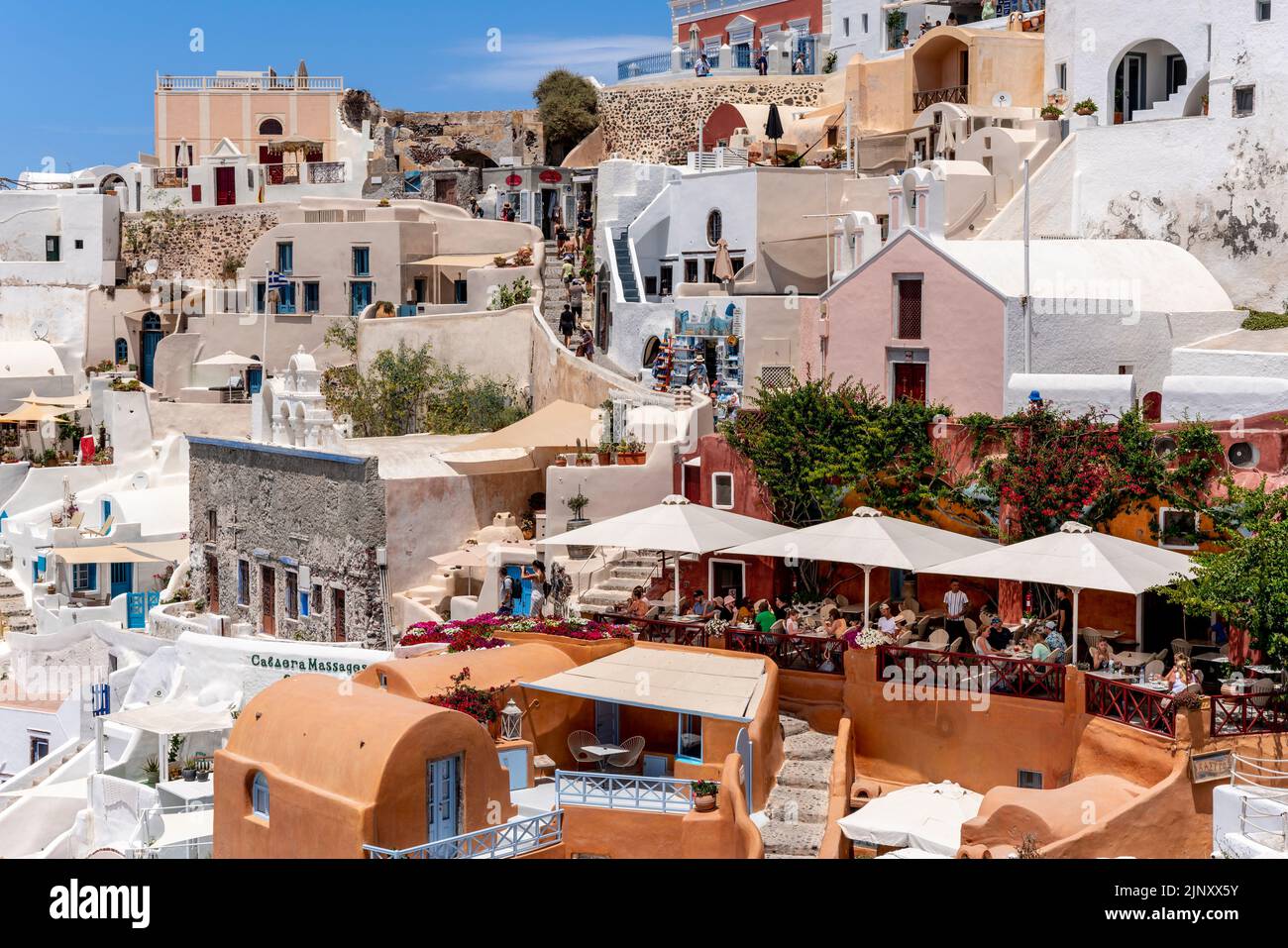 Gente comiendo en un restaurante con vistas al mar Egeo en la ciudad de Oia, Santorini, Islas Griegas, Grecia. Foto de stock