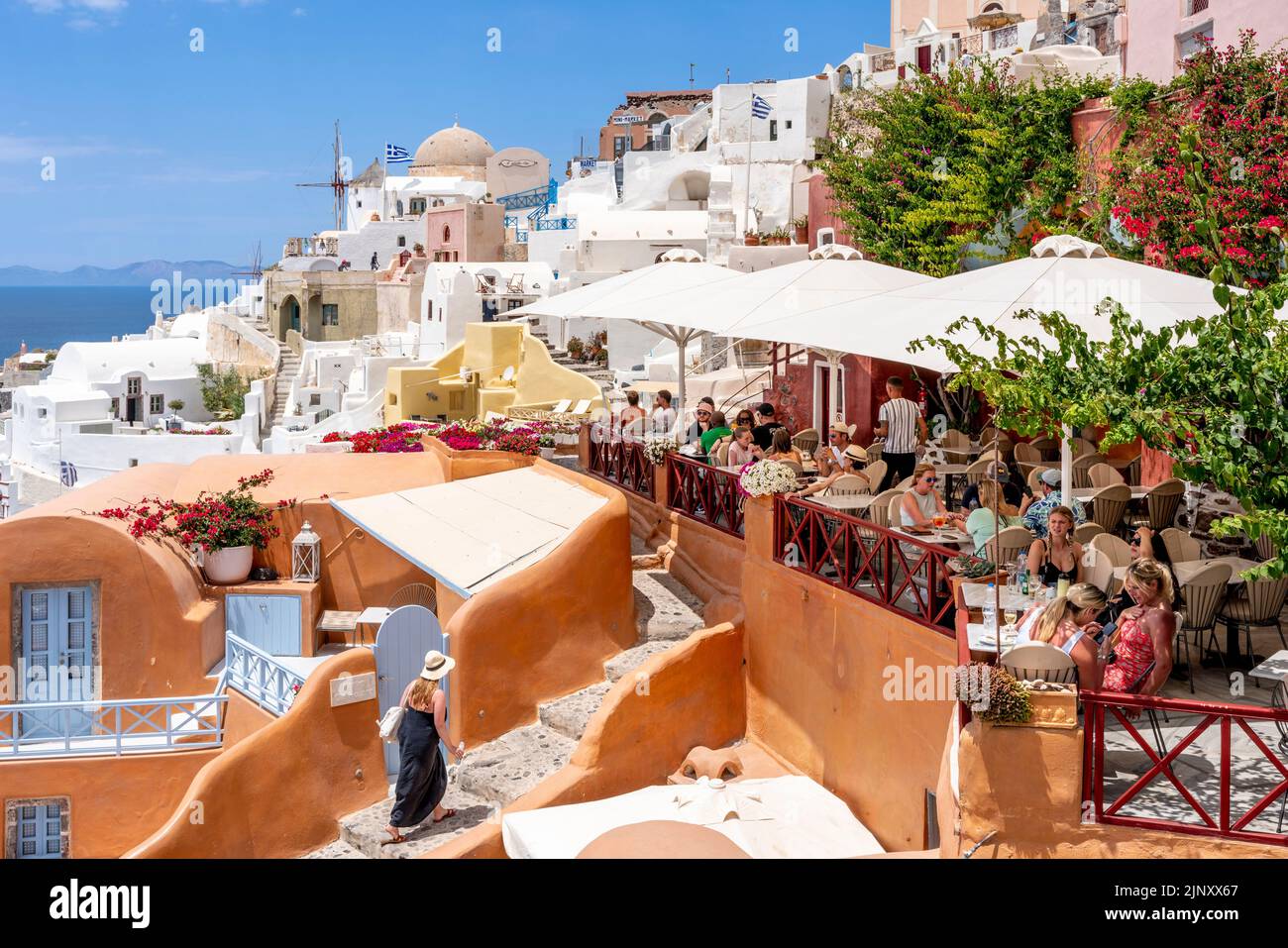 Gente comiendo en un restaurante con vistas al mar Egeo en la ciudad de Oia, Santorini, Islas Griegas, Grecia. Foto de stock