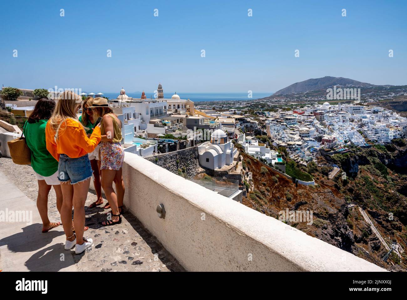 Un grupo de mujeres jóvenes visitantes en Un mirador con vistas a la ciudad principal de Thira en Santorini, las islas griegas, Grecia. Foto de stock