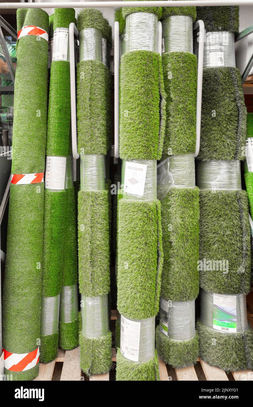 Rollos de hierba plástica de varios tonos en un centro de jardín para su uso en jardines como césped Foto de stock