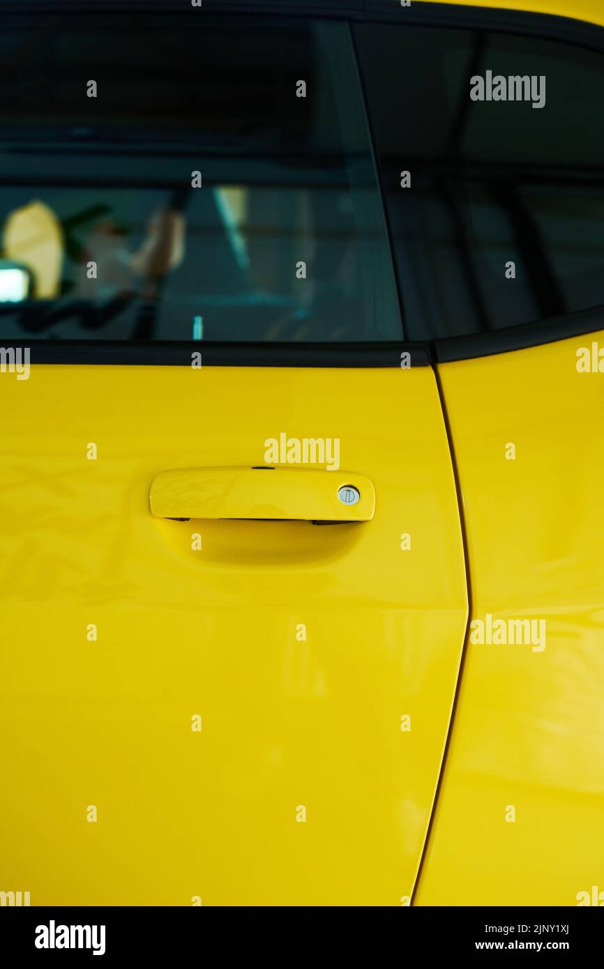 Parte de puerta y ventana de coche eléctrico moderno de color amarillo parado en garaje o estación de gasolina y esperando reparación o repostaje Foto de stock