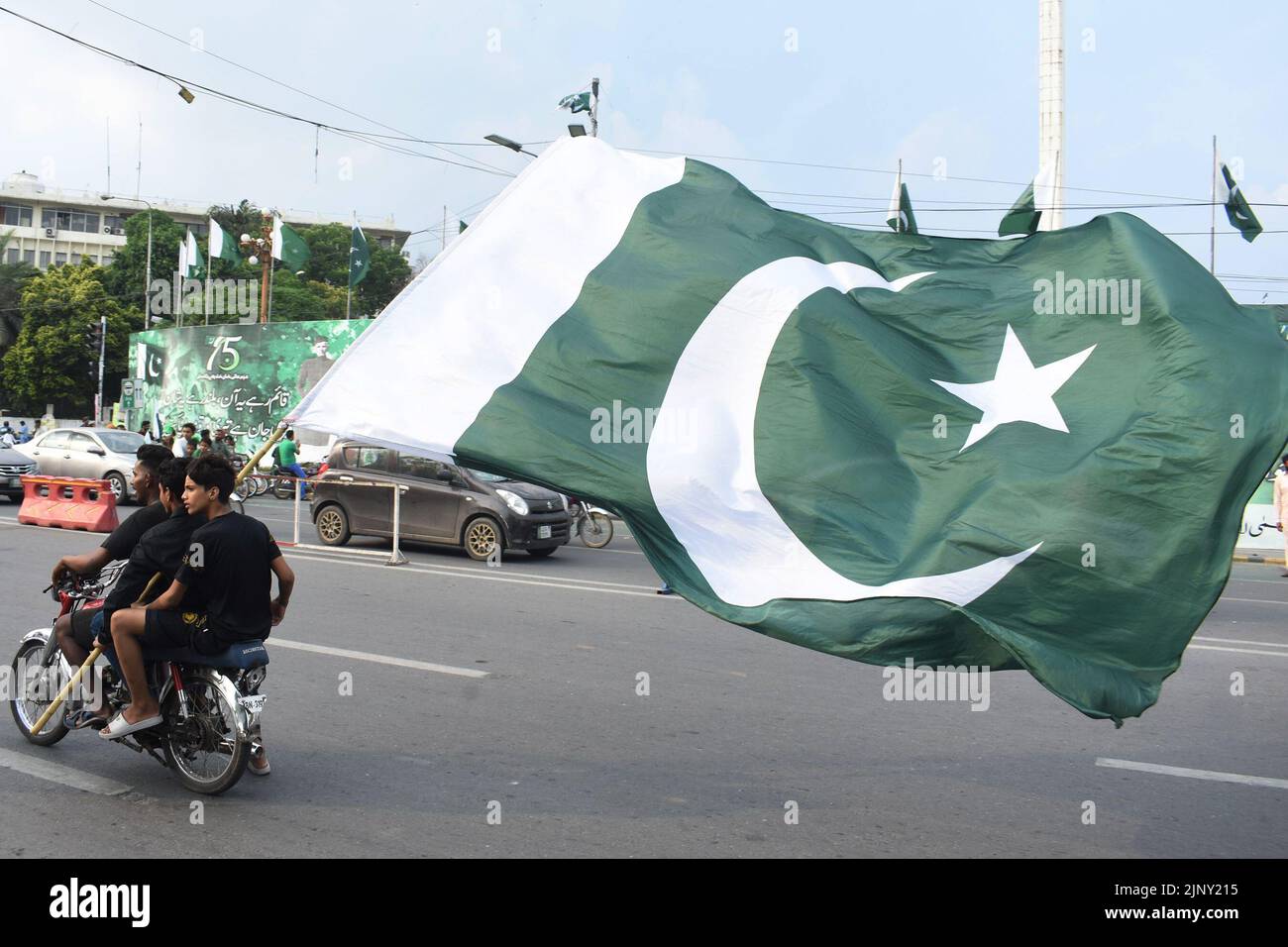Lahore, Pakistán. 14th de Ago de 2022. La gente sostiene una bandera nacional paquistaní en una motocicleta para celebrar el Día de la Independencia del país en Lahore, Pakistán, el 14 de agosto de 2022. Crédito: Sajjad/Xinhua/Alamy Live News Foto de stock