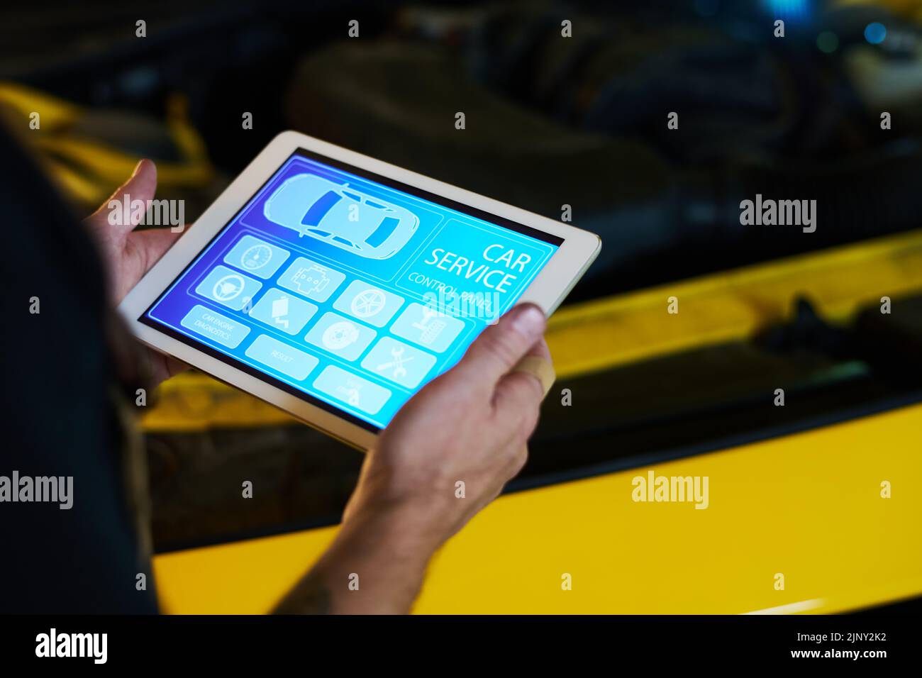 Manos de hombre mecánico de mantenimiento servicio de mantenimiento tableta con página de inicio con iconos en pantalla mientras está de pie en coche Foto de stock
