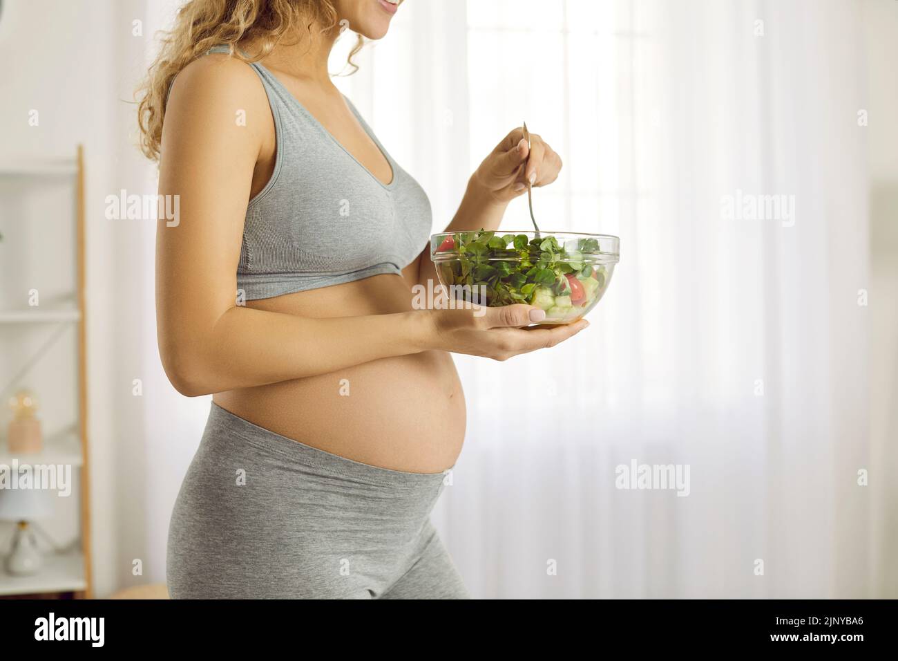Tazón de ensalada verde vegetal en manos de una mujer embarazada que controla su dieta durante el embarazo. Foto de stock