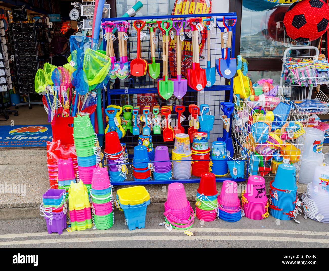 Exhibición al borde de la carretera de coloridos inflables y juguetes de playa en una tienda junto al Cobb en Lyme Regis en la Costa Jurásica en Dorset, al sur de Inglaterra Foto de stock