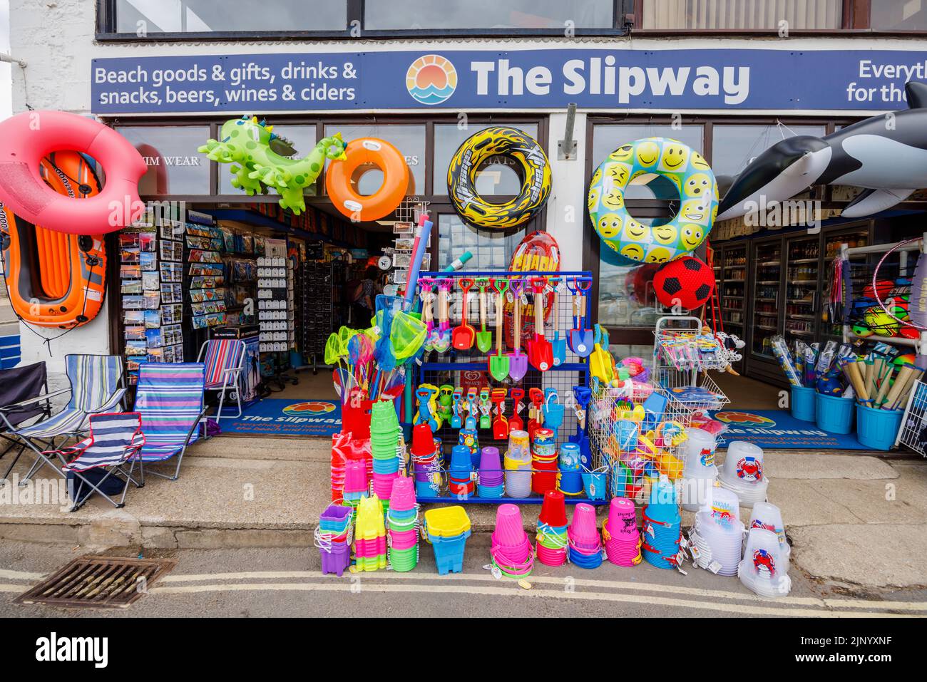 Exhibición al borde de la carretera de coloridos inflables y juguetes de playa en una tienda junto al Cobb en Lyme Regis en la Costa Jurásica en Dorset, al sur de Inglaterra Foto de stock
