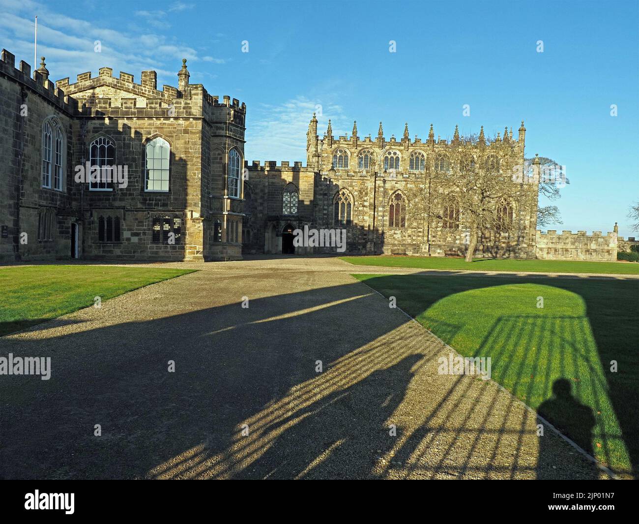 Largas sombras de puertas de figuras y entrada arqueada sobre el césped y caminos que conducen al majestuoso Bishop's Palace, Bishop Auckland, County Durham, Inglaterra, Reino Unido Foto de stock
