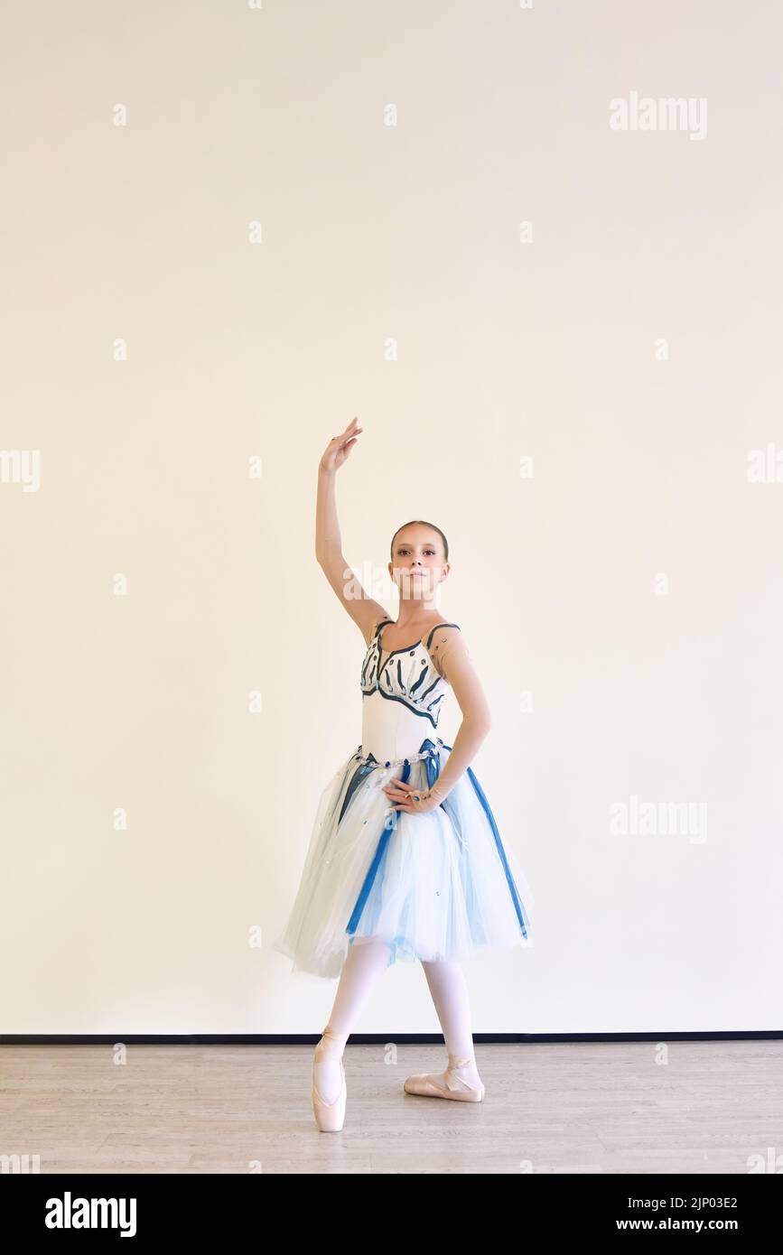 Una joven bailarina encantadora en un vestido practicando ballet posa en el estudio Foto de stock