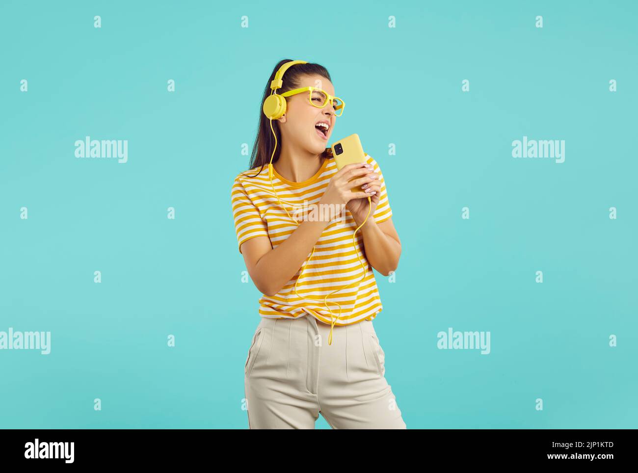Alegre mujer divertida en auriculares canta y escucha música con la aplicación para smartphone para listas de reproducción. Foto de stock