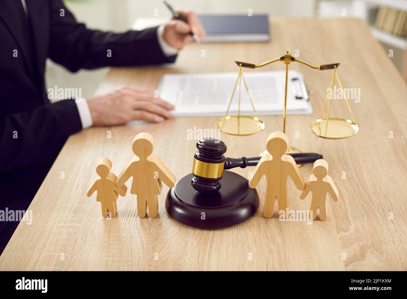 Las figuras de la familia están separadas por el martillo del juez, que simboliza el caso de divorcio y la custodia del niño Foto de stock