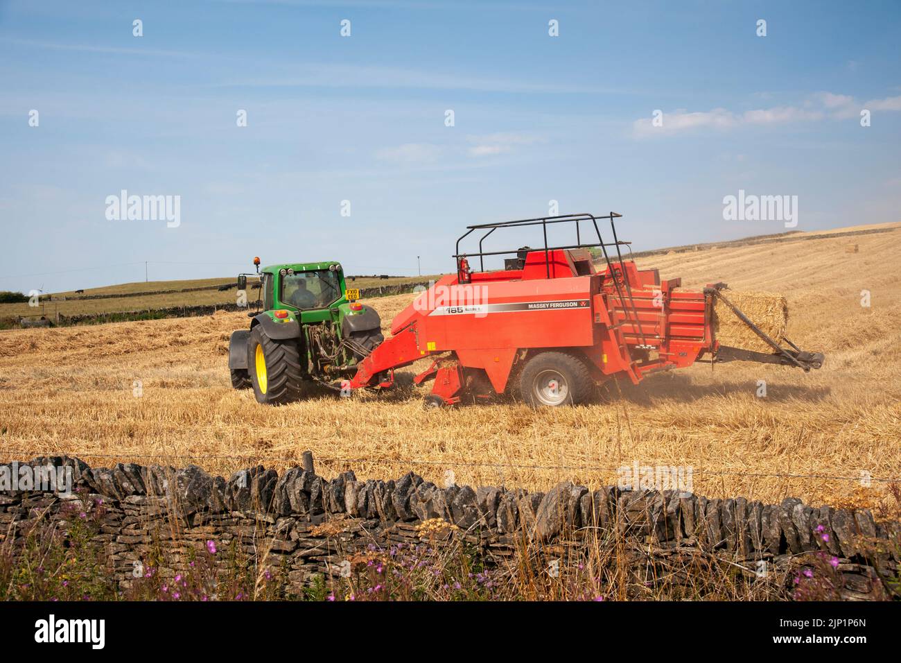 Tractor John Deer tirando de una máquina de rescate en un campo en una granja cerca de Langestt, South Yorkshire durante la sequía de 2022 Foto de stock