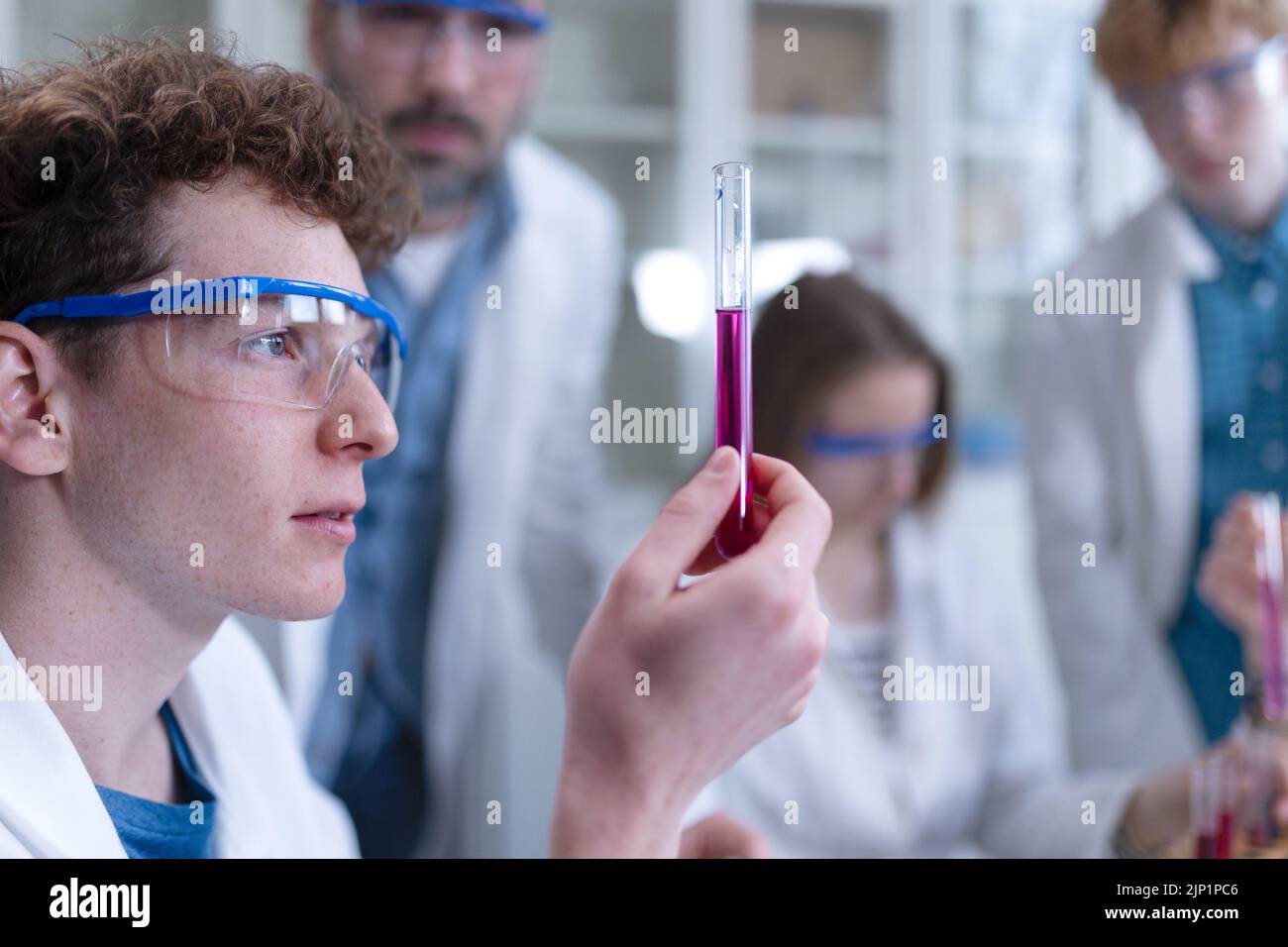 Estudiantes de ciencias con profesor que hace experimentos químicos en el laboratorio de la universidad. Foto de stock