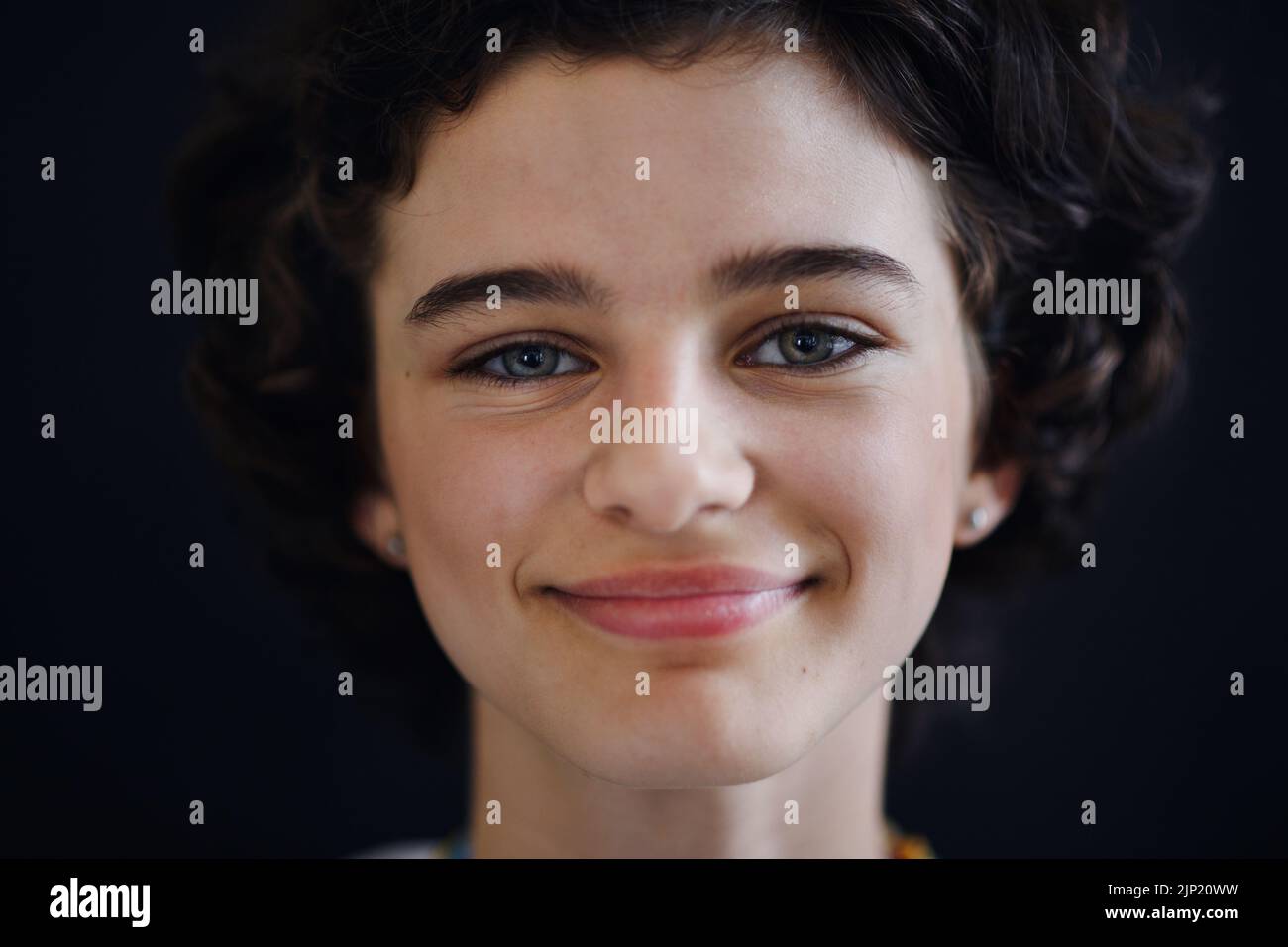 Retrato de una joven adolescente segura y bella mirando la cámara, sobre fondo negro, primer plano Foto de stock