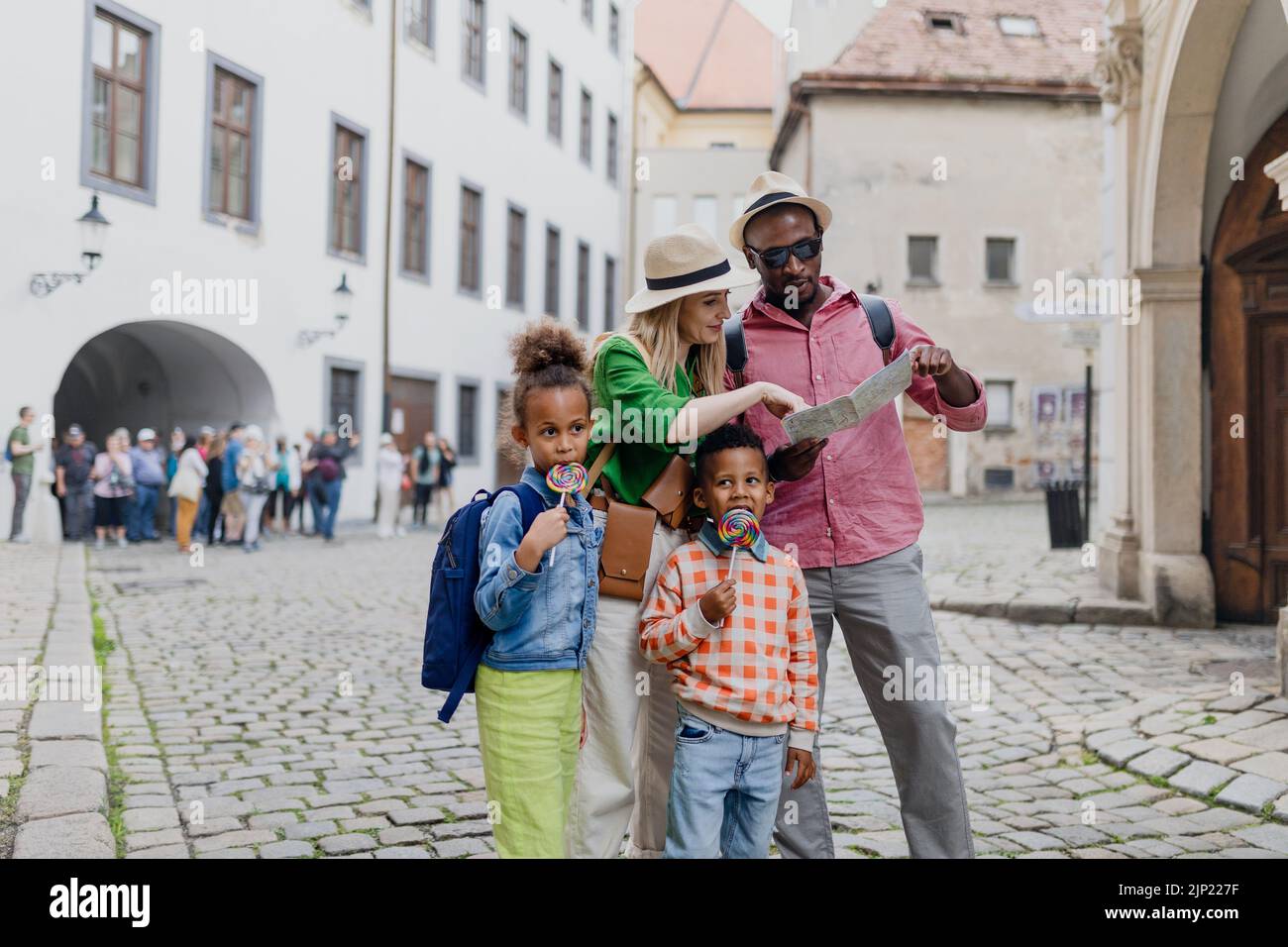 Familia multirracial viaja con maletas, caminando por el casco antiguo de la ciudad. Foto de stock