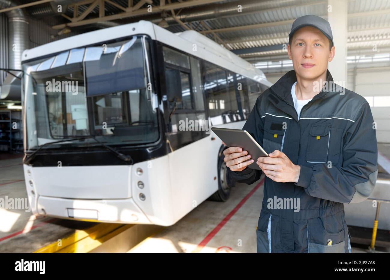 Técnico con tablet digital en el fondo del autobús en el garaje Foto de stock