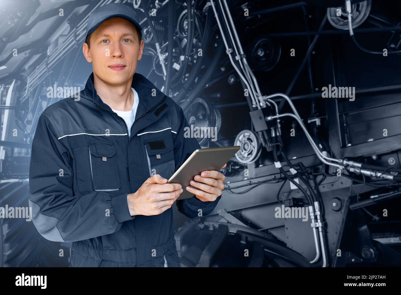Técnico de servicio con una tableta digital sobre el fondo del tractor con el capó abierto Foto de stock