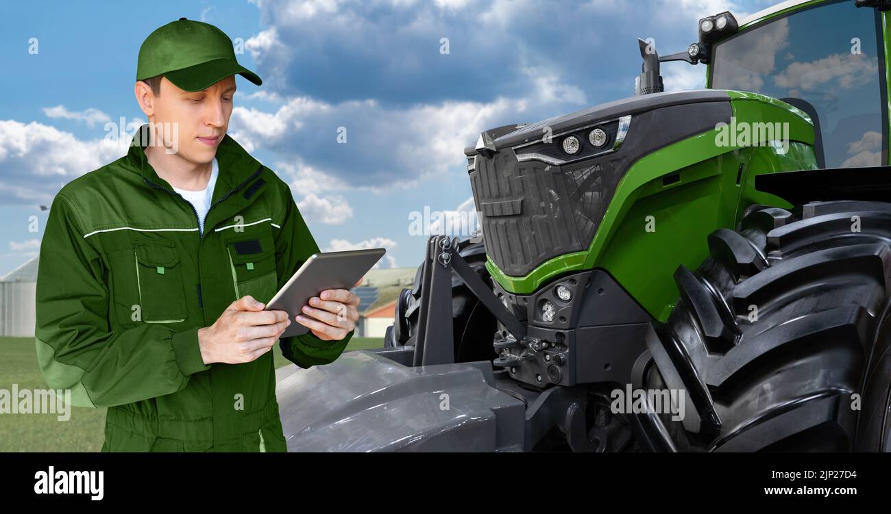 Agricultor con una tableta digital en el fondo de un tractor agrícola Foto de stock
