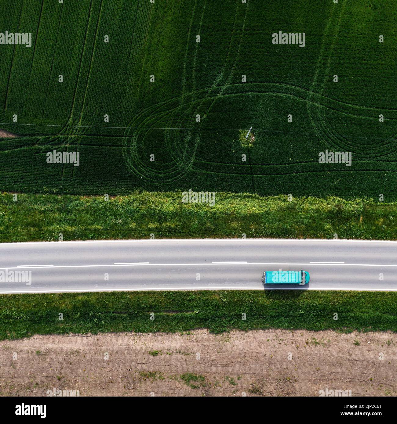 Foto aérea de un vehículo camioneta azul conduciendo a lo largo de una autopista a través de un paisaje rural, con drone pov directamente encima Foto de stock