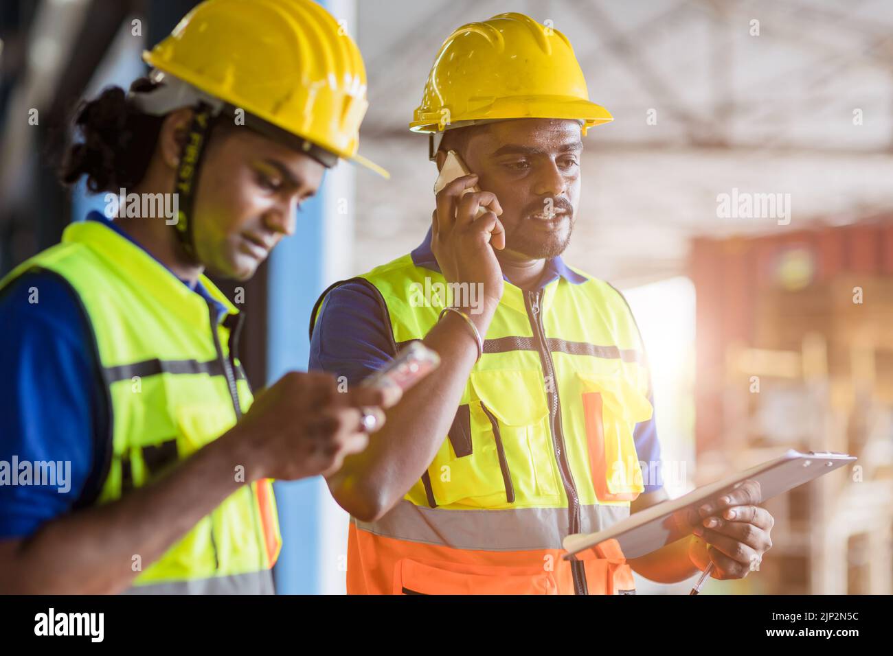 Ingeniero capataz indio que utiliza teléfono de comunicación llamada y dispositivo de tecnología en el lugar de trabajo de la fábrica Foto de stock