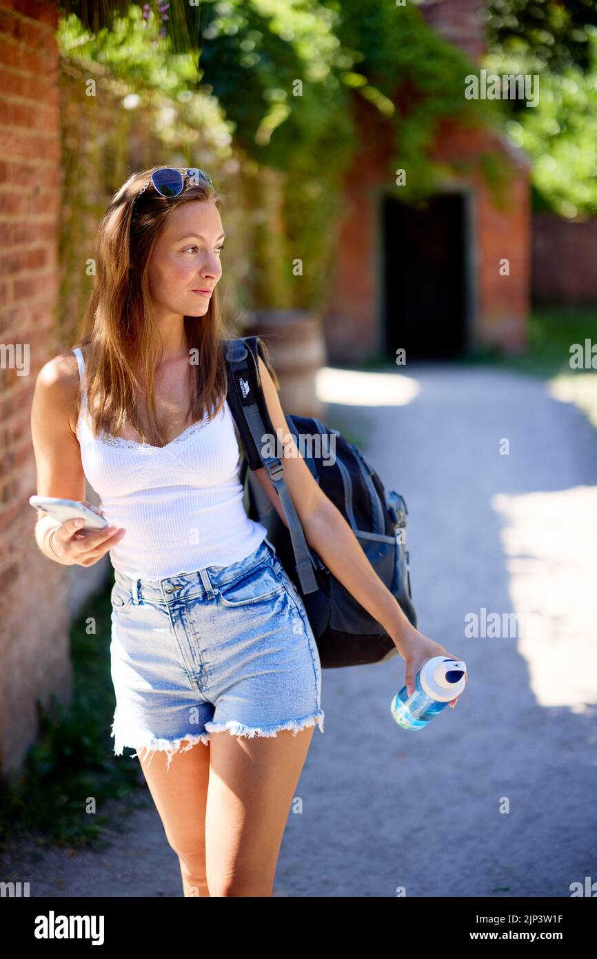 Mujer caminando llevando su teléfono móvil y una botella de agua Foto de stock