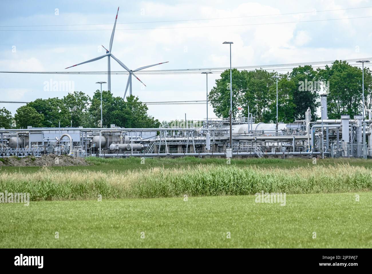 Vista de un sitio de extracción de gas natural con turbinas eólicas en el fondo. Campo de gas de Groningen, Países Bajos. Foto de stock
