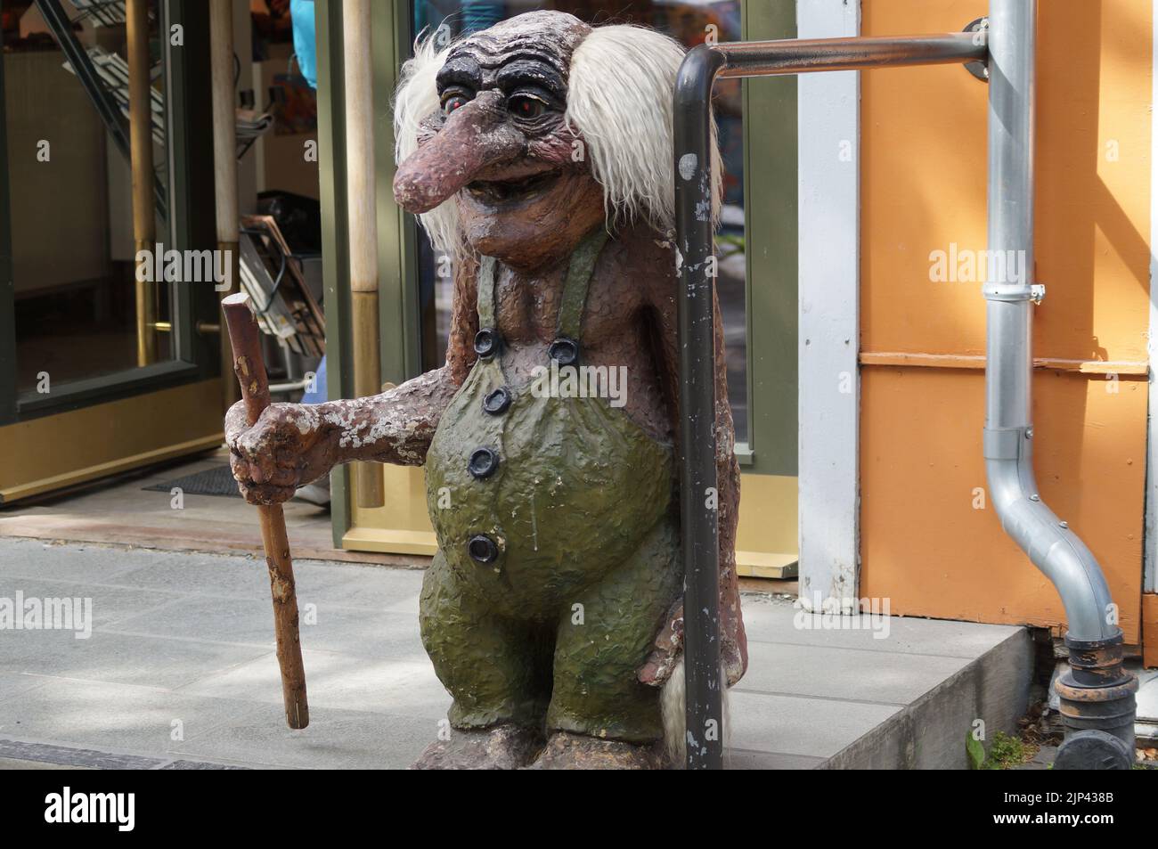 Primer plano de una escultura de troll que sostiene un palo de madera frente a una tienda en Noruega Foto de stock