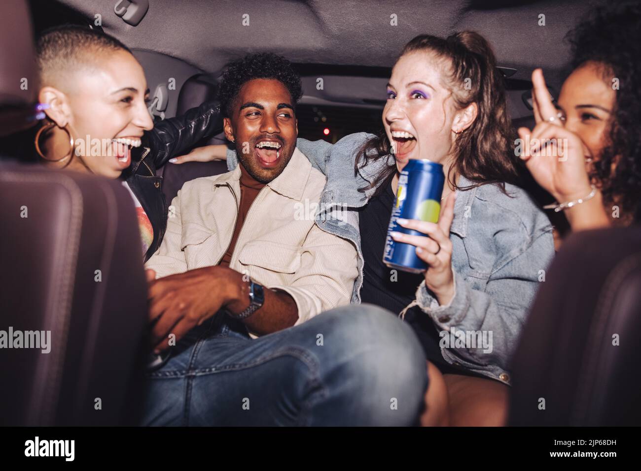 Amigos alegres divirtiéndose en el asiento trasero de un coche. Grupo de gente joven diversa riendo juntos mientras se sentaban en un taxi. Cuatro amigos felices havi Foto de stock