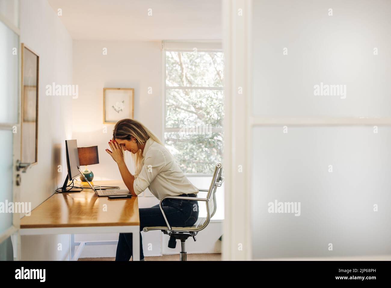 Mujer de negocios teniendo un dolor de cabeza en su oficina. Mujer de negocios con exceso de trabajo que experimenta fatiga laboral mientras se sienta delante de un portátil. Foto de stock