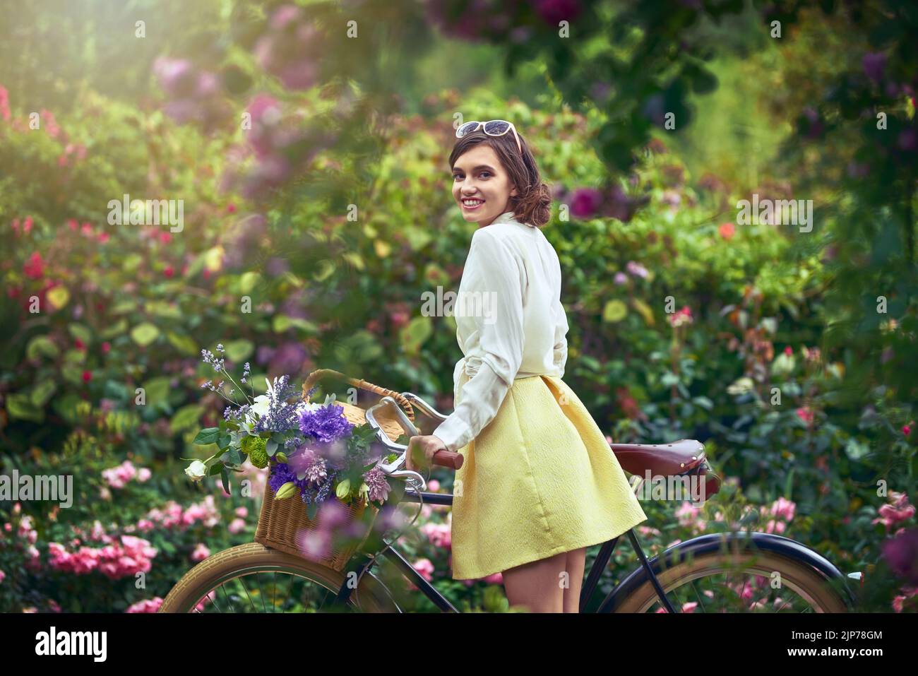 Su belleza brilla más que el pintoresco paisaje. Retrato de una joven atractiva en bicicleta al aire libre. Foto de stock