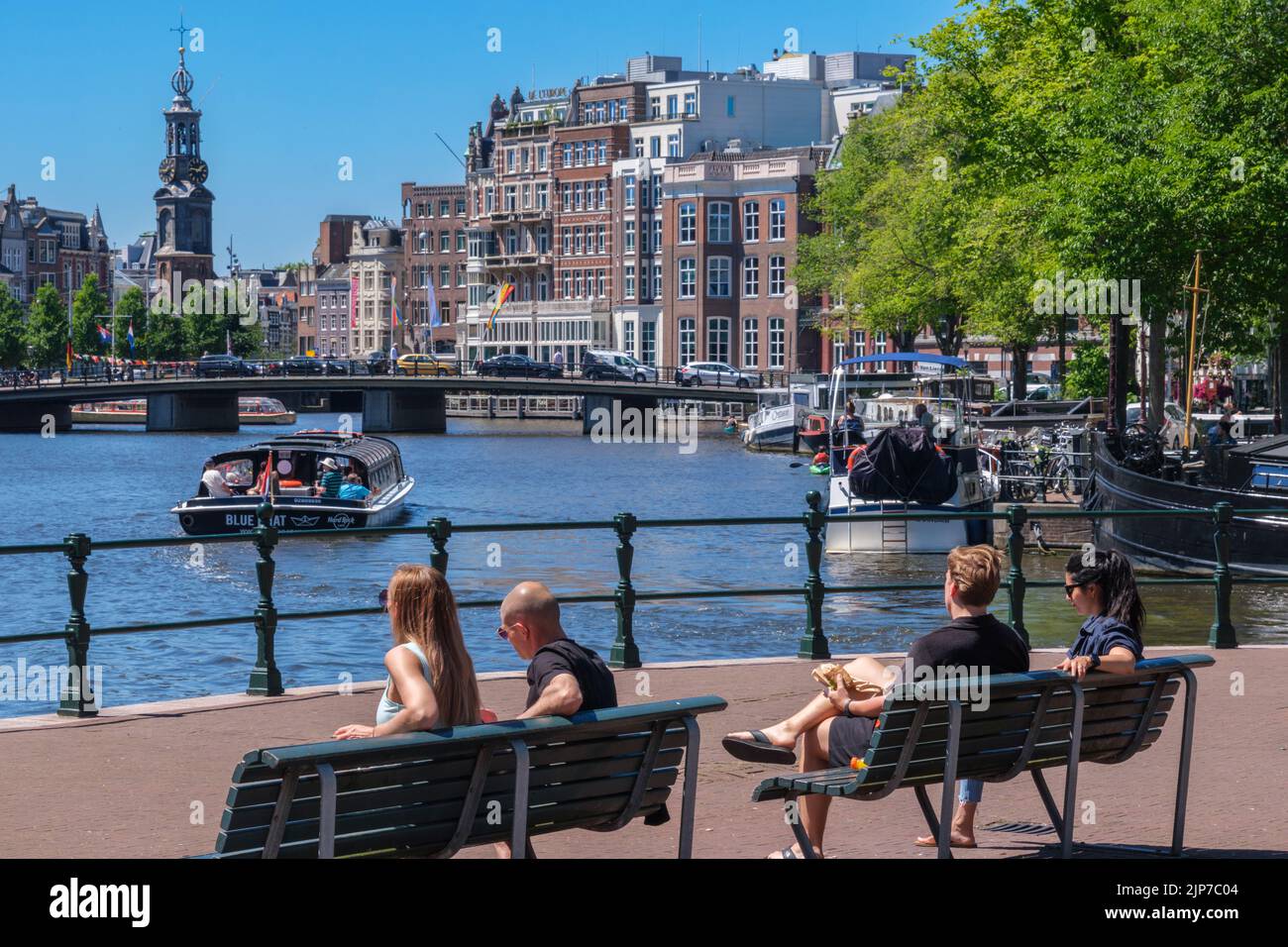 Ámsterdam, Países Bajos - 22 de junio de 2022: Gente sentada en bancos en la orilla del río Amstel Foto de stock