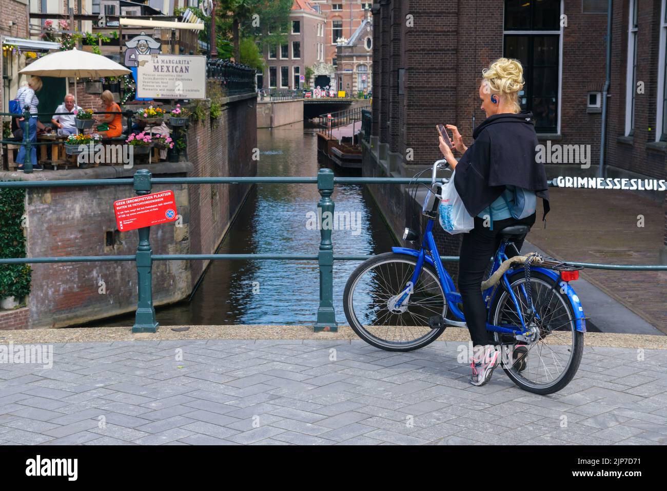 Ámsterdam, Países Bajos - 21 de junio de 2022: Mujer en bicicleta en el puente Grimnessesluis Foto de stock