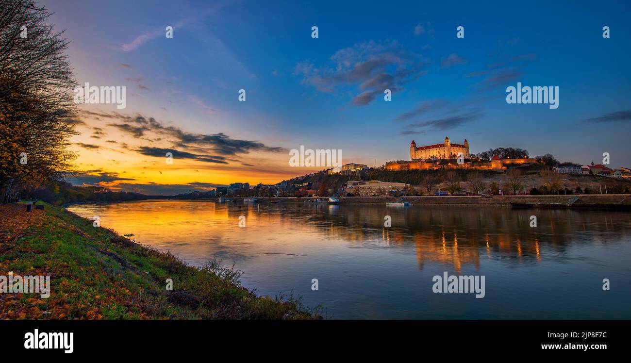 Puesta de sol sobre el castillo de Bratislava, el parlamento eslovaco y el río Danubio en Eslovaquia Foto de stock