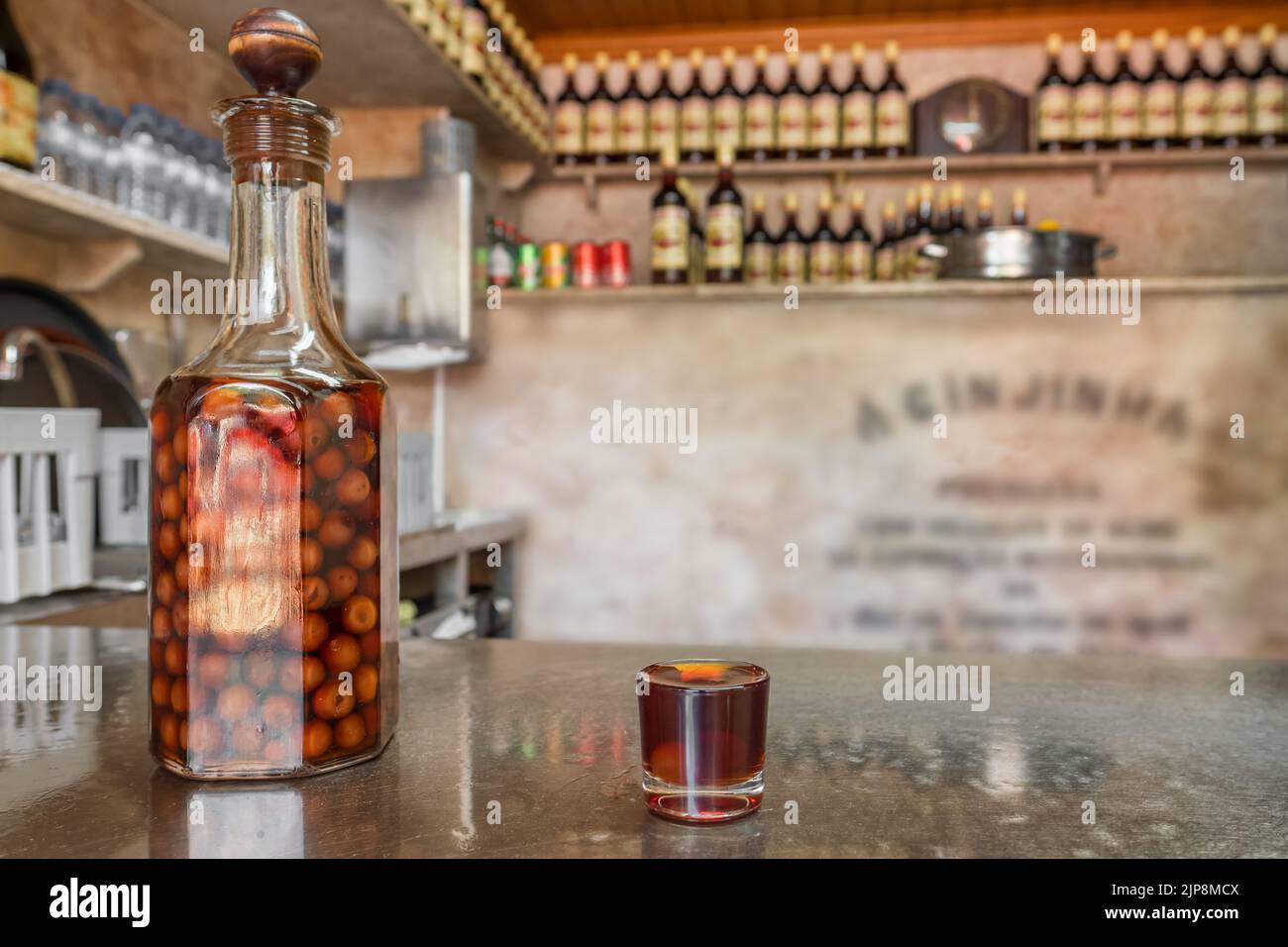 Botella y vaso de vidrio con un licor de cereza tradicional Ginjinha en Lisboa, Portugal. Foto de stock
